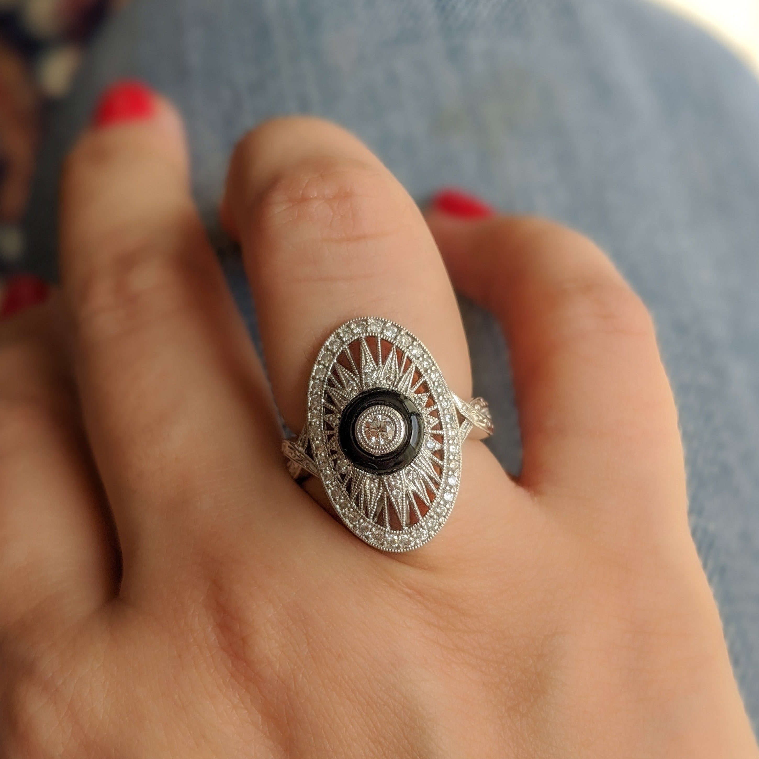 White gold diamond ring with onyx centre worn on woman’s finger.