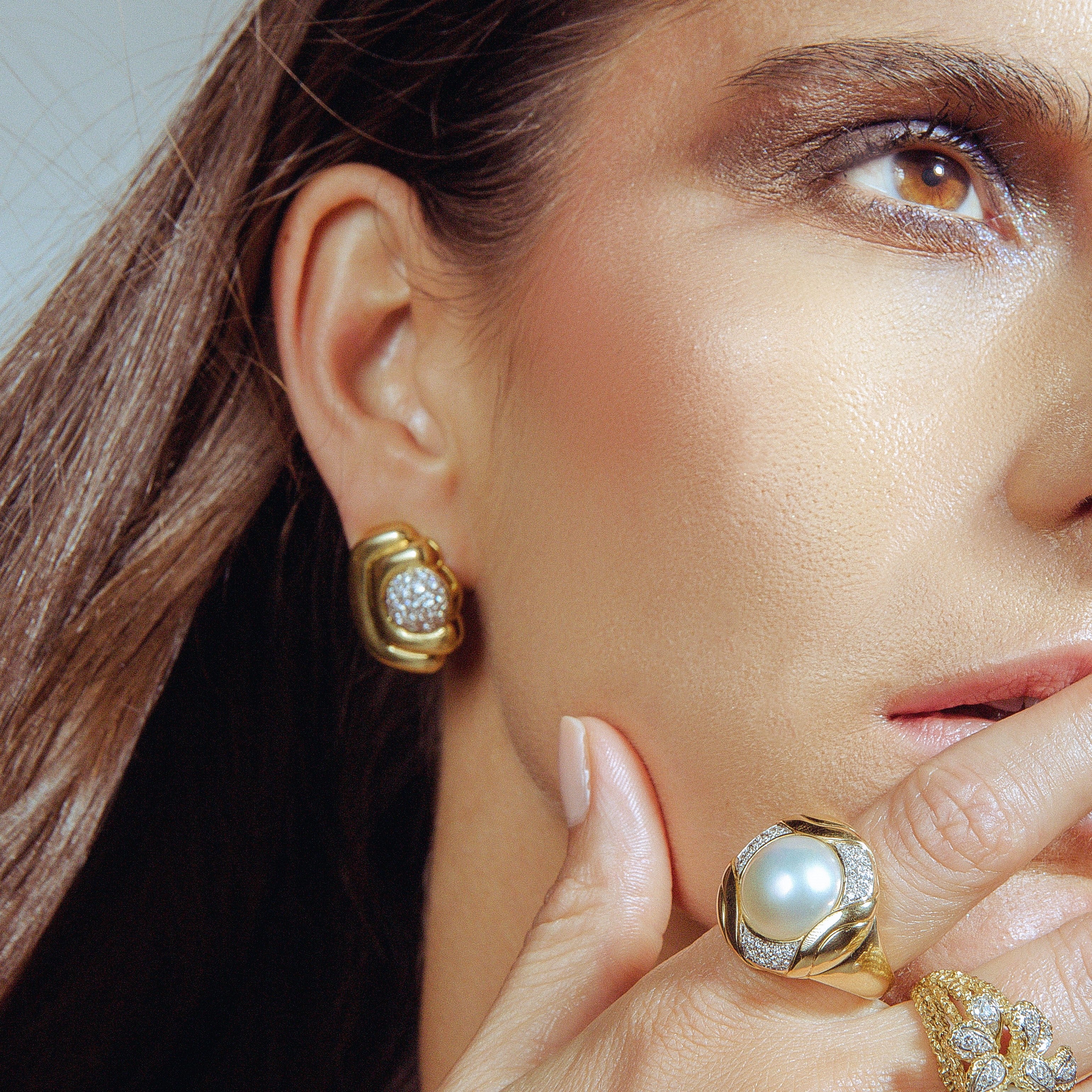 Woman wearing vintage gold and diamond earrings and pear ring. 