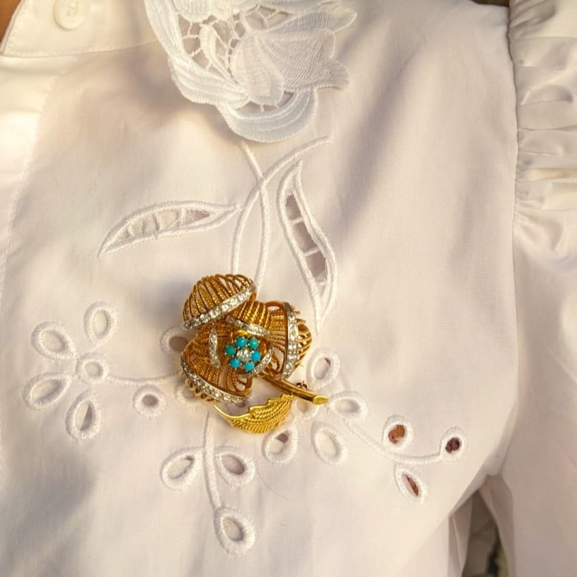 1960s gold and platinum flower brooch pinned on a white shirt. 