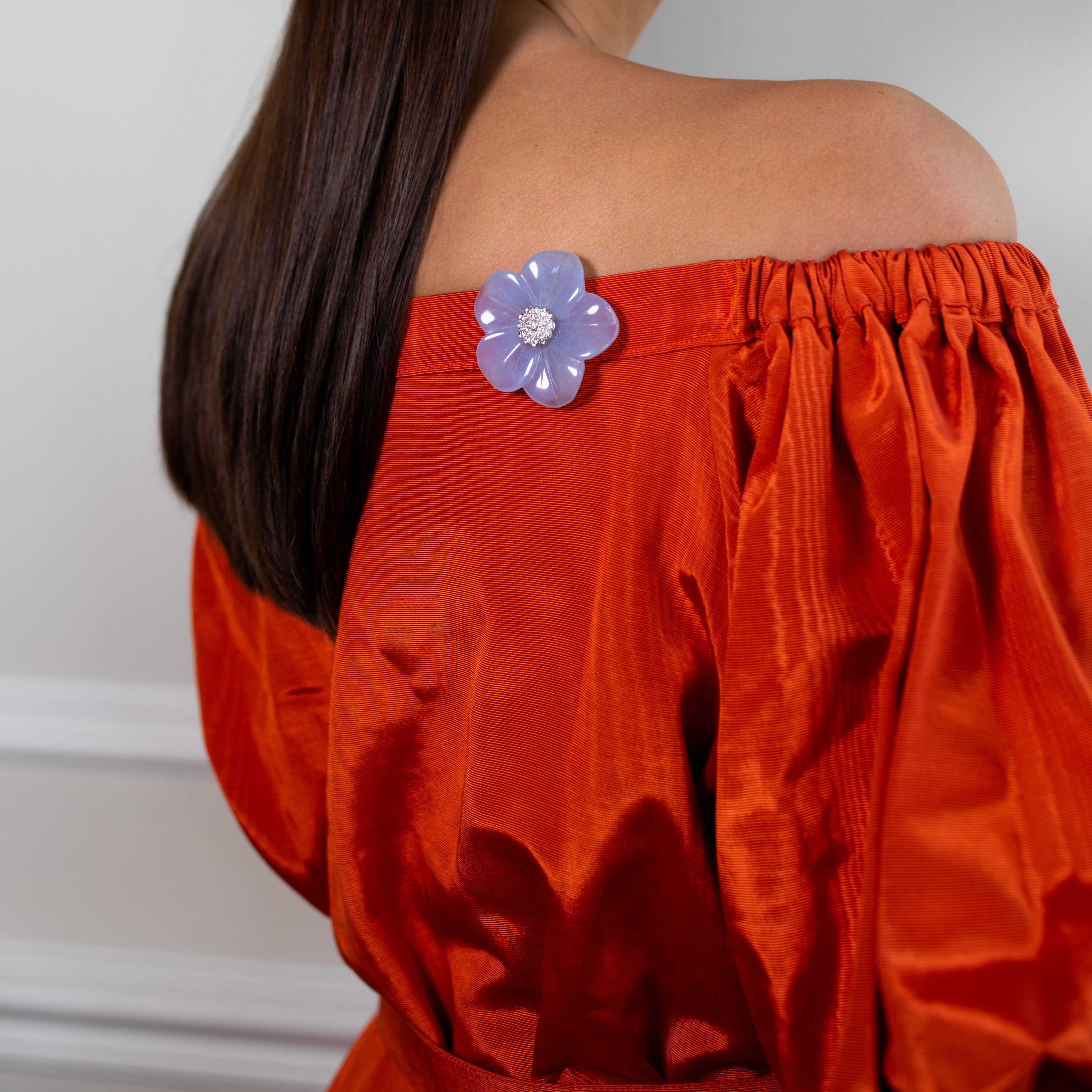 Vintage flower brooch worn on a woman’s back on a red low-cut top.
