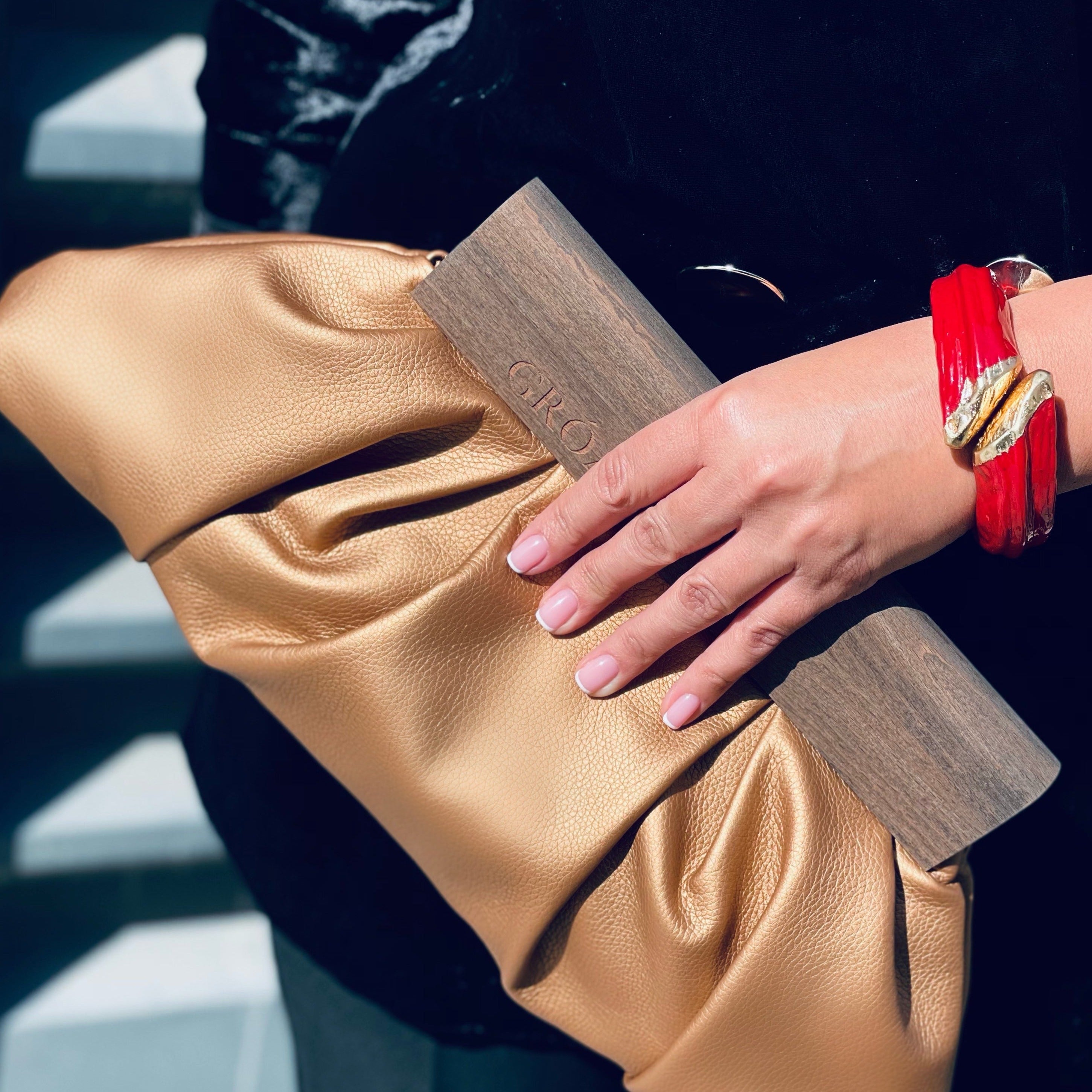 Angela Caputi plastic bangle combined with goldish envelope clutch bag