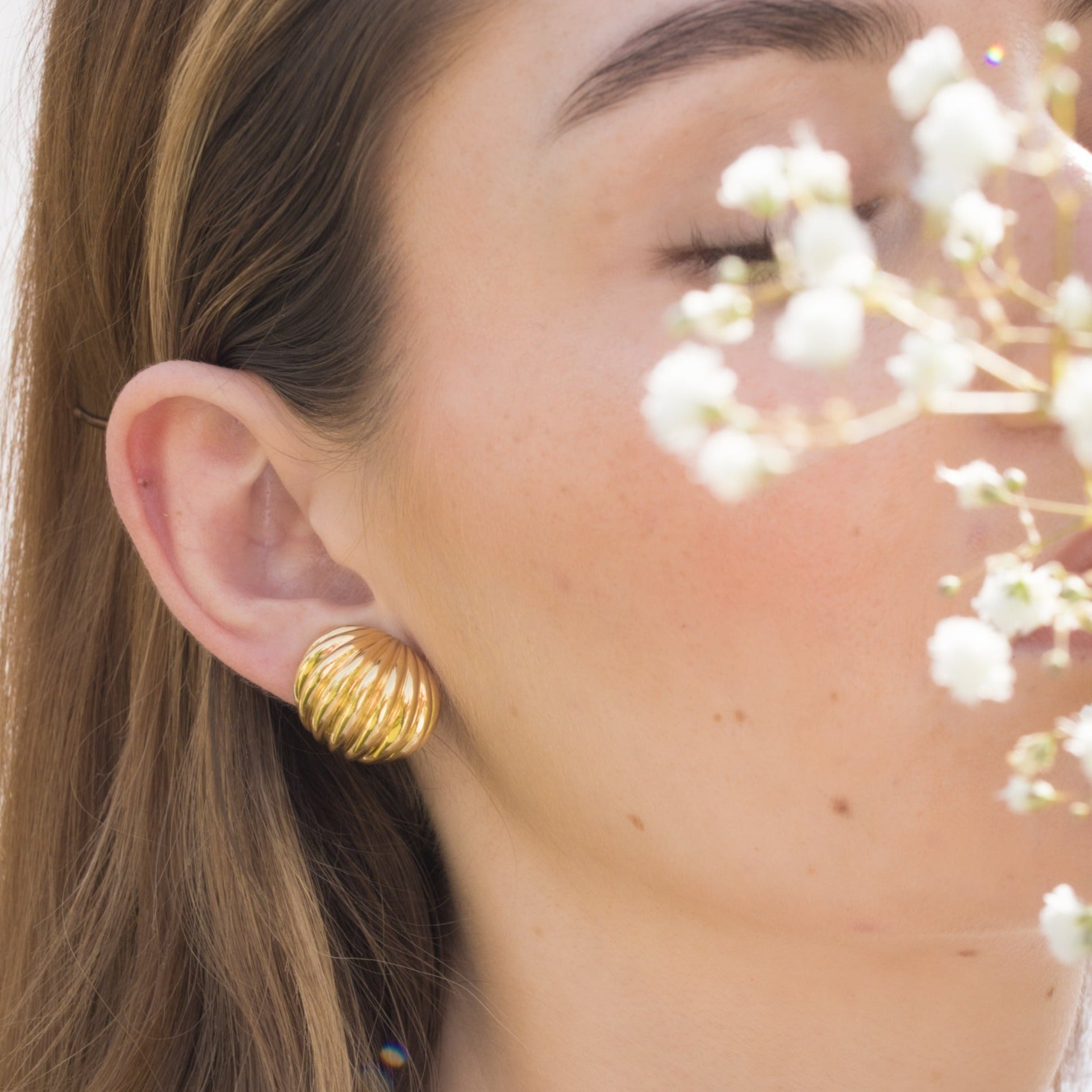 Woman in profile wearing a vintage gold earring.