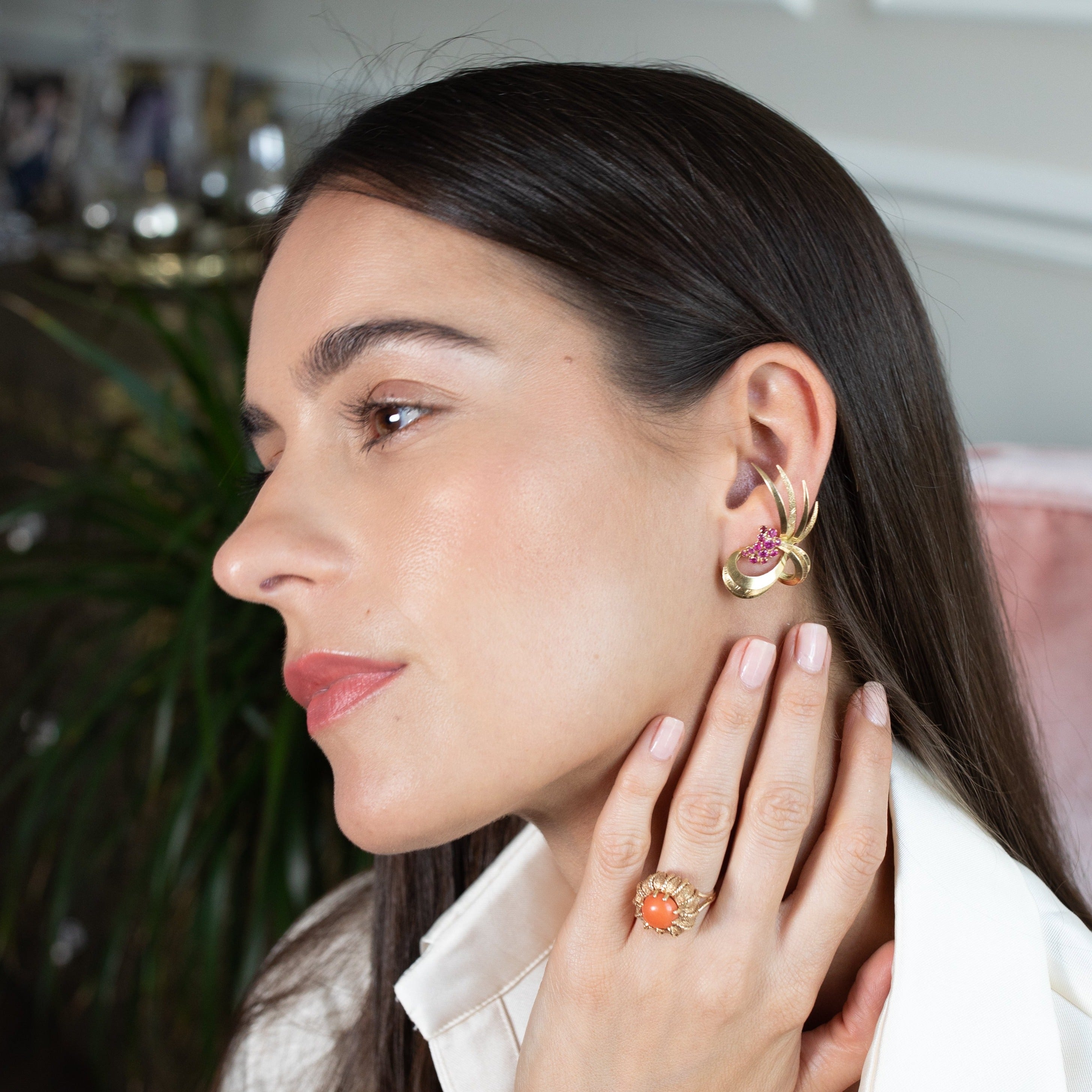 Woman wearing a vintage gold coral ring and statement earrings. 