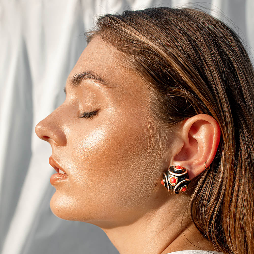 Profile-facing woman wearing colourful earrings.