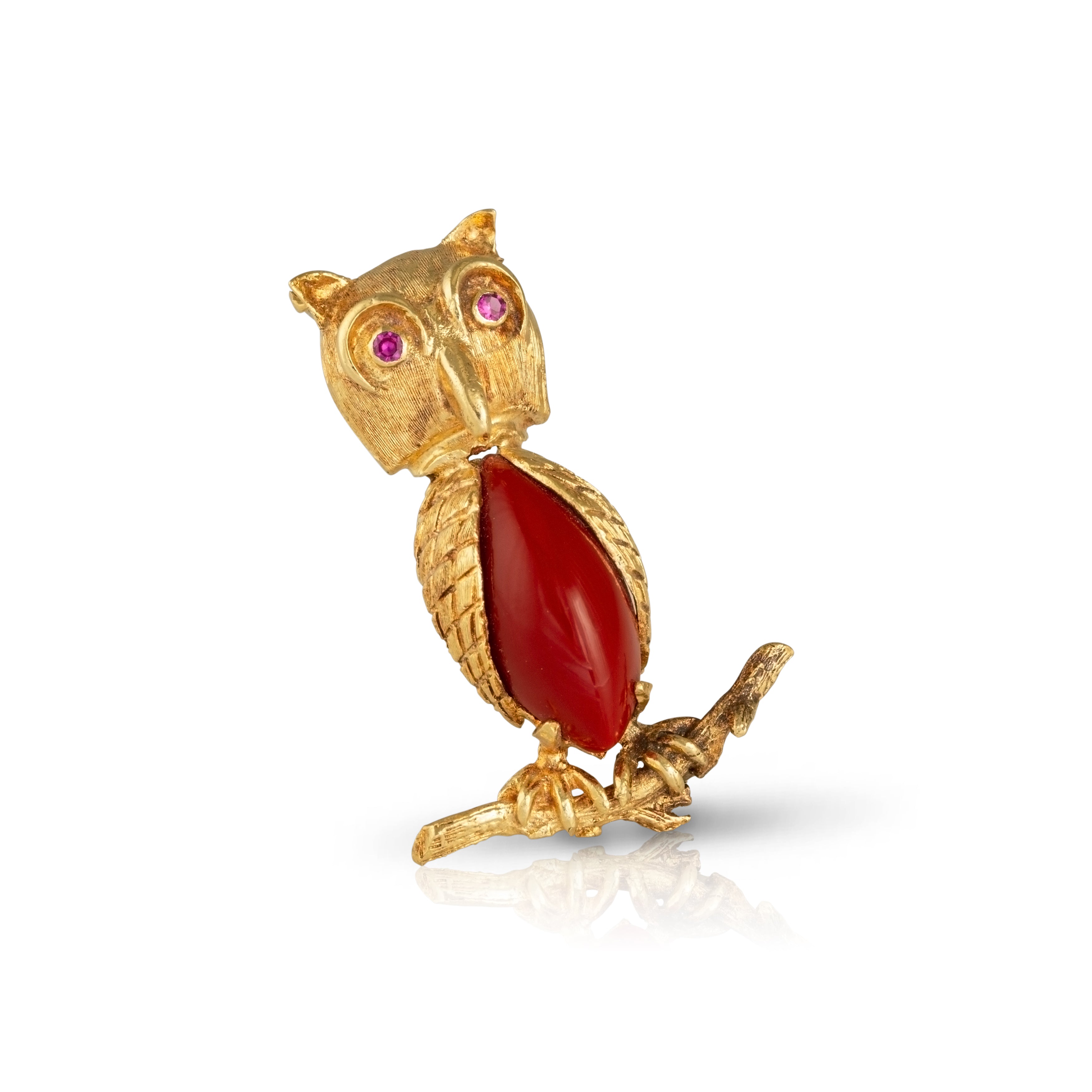 ilted gold owl brooch with red glass and rubies sitting on a branch.