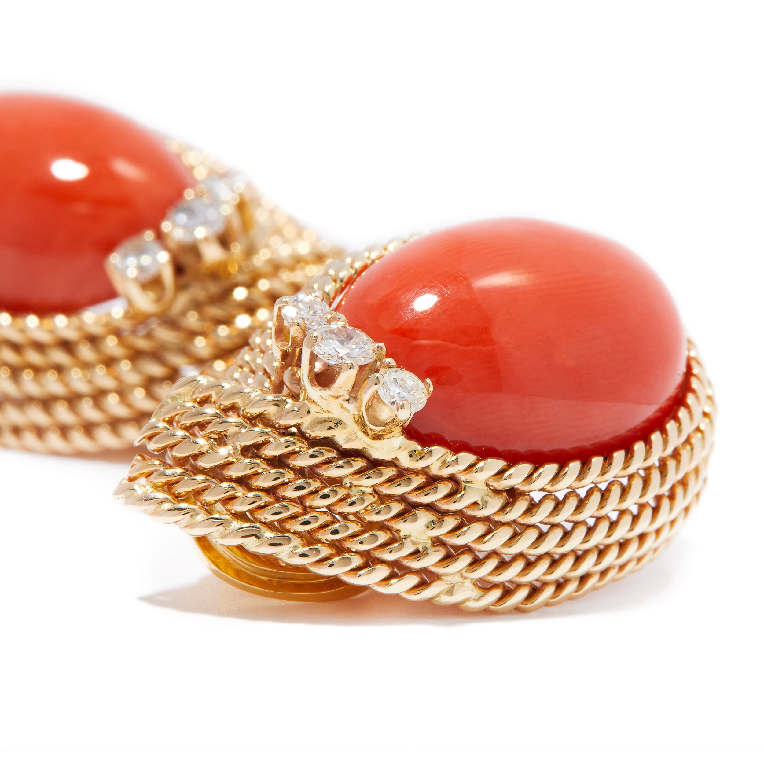 Up close view of vintage designer earrings with gold, corals, and diamonds