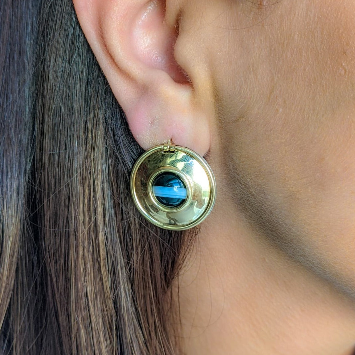 Reversible Paloma Picasso earrings worn on the gold side on a woman’s ear.