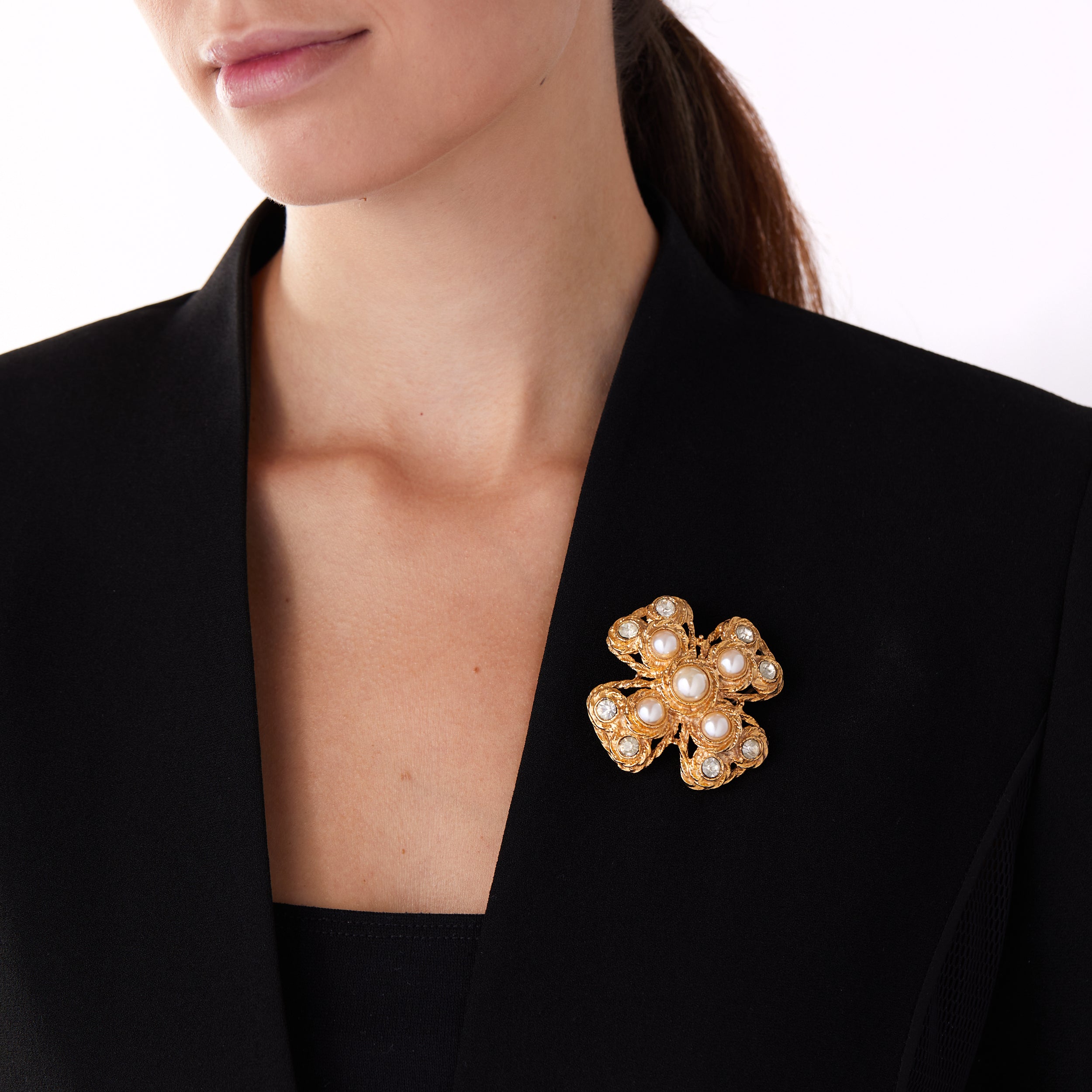 Vintage costume cross pin brooch worn on a blazer lapel