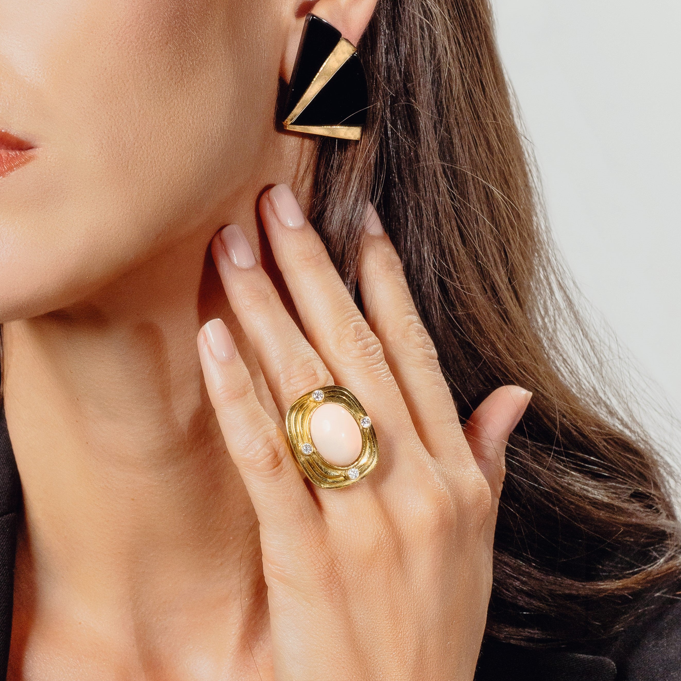 Woman’s face and hand wearing vintage ring and earrings.