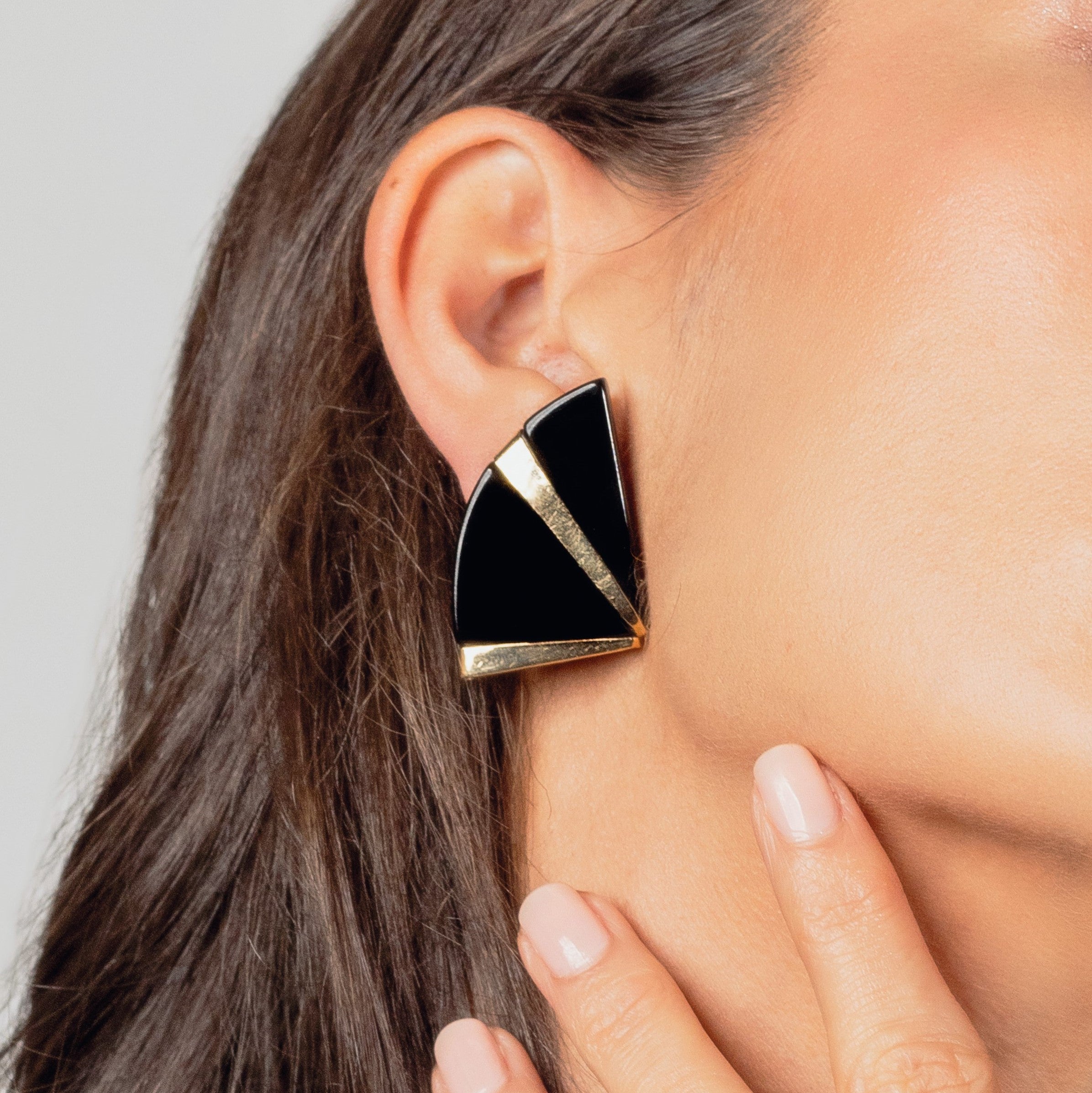 Triangular geometric earrings worn on a woman’s ear.