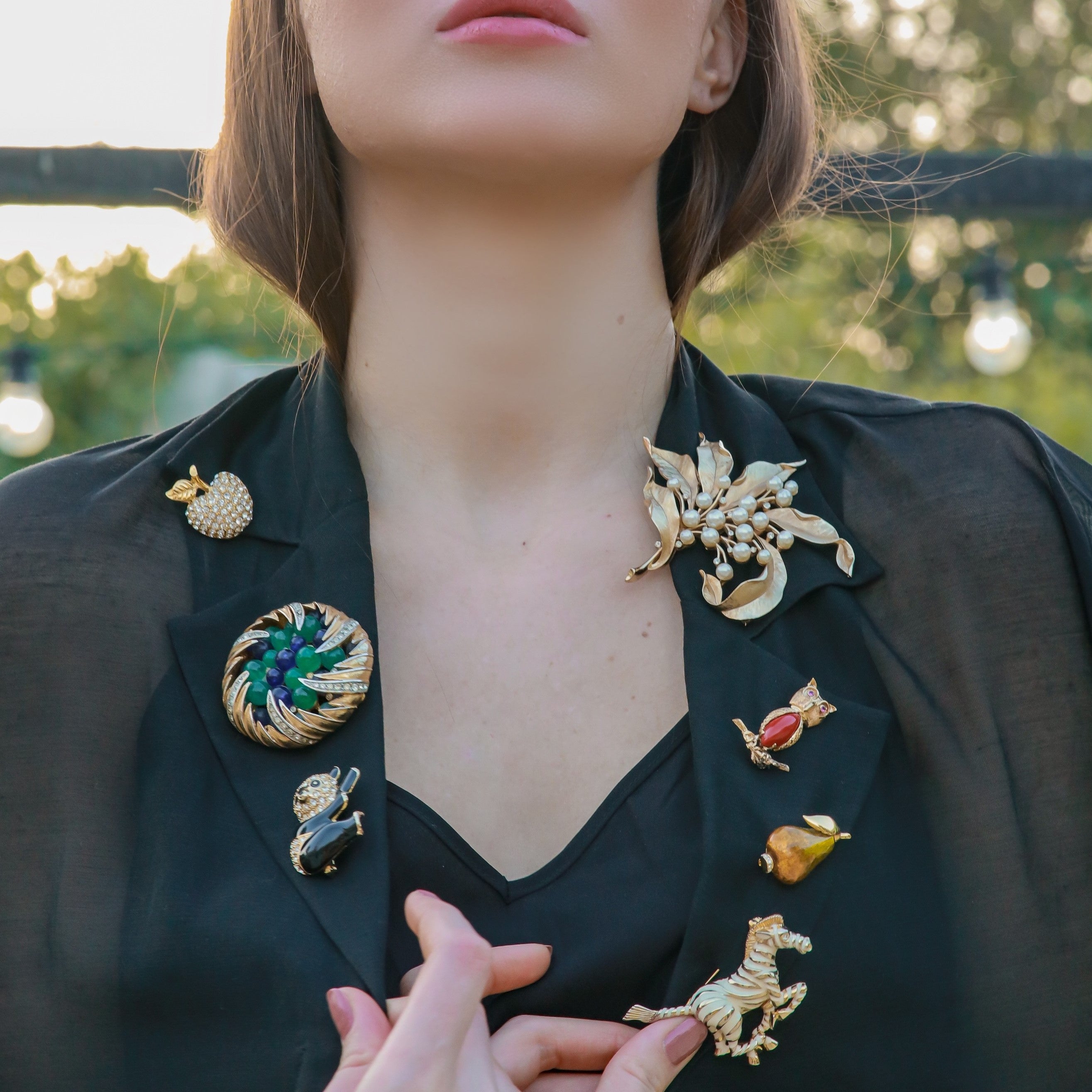 Collection of vintage brooches worn on a woman’s black blazer lapel. 