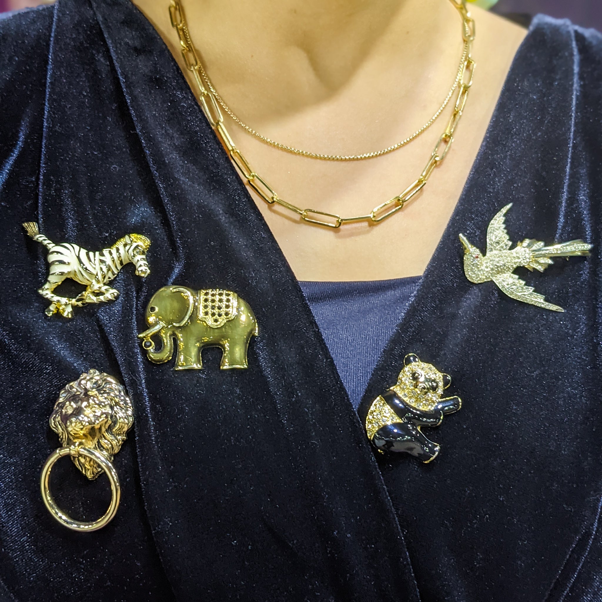 Collection of YazJewels vintage animal brooches worn on woman’s shirt
