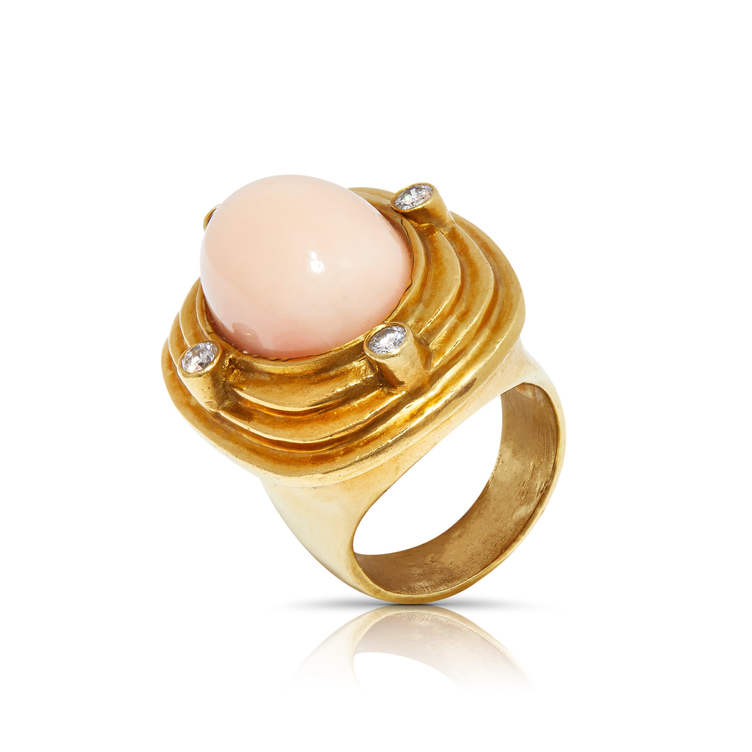 Gold statement ring with coral cabochon and diamonds in tilted view.
