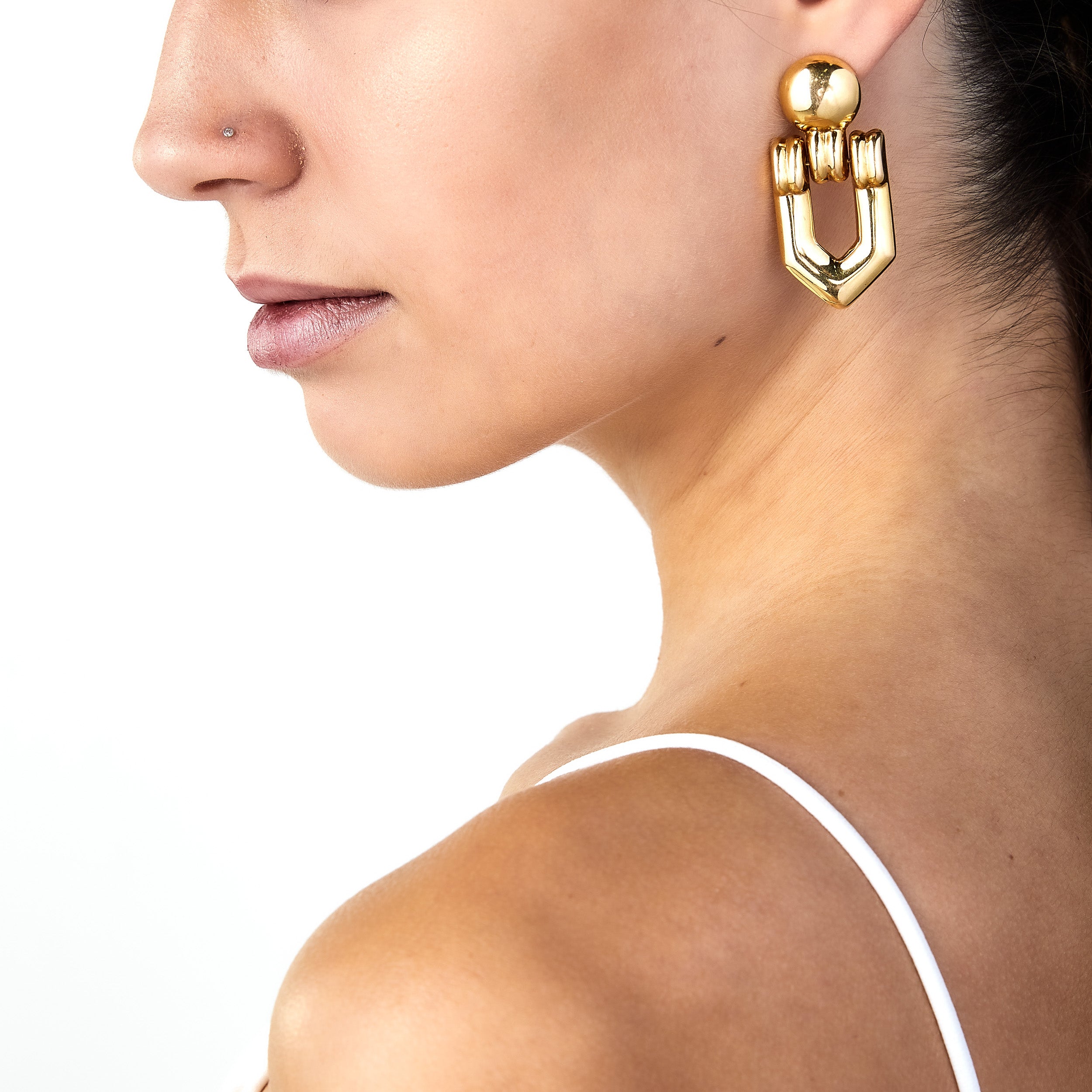 intage gold door knocker earring worn on woman’s ear.