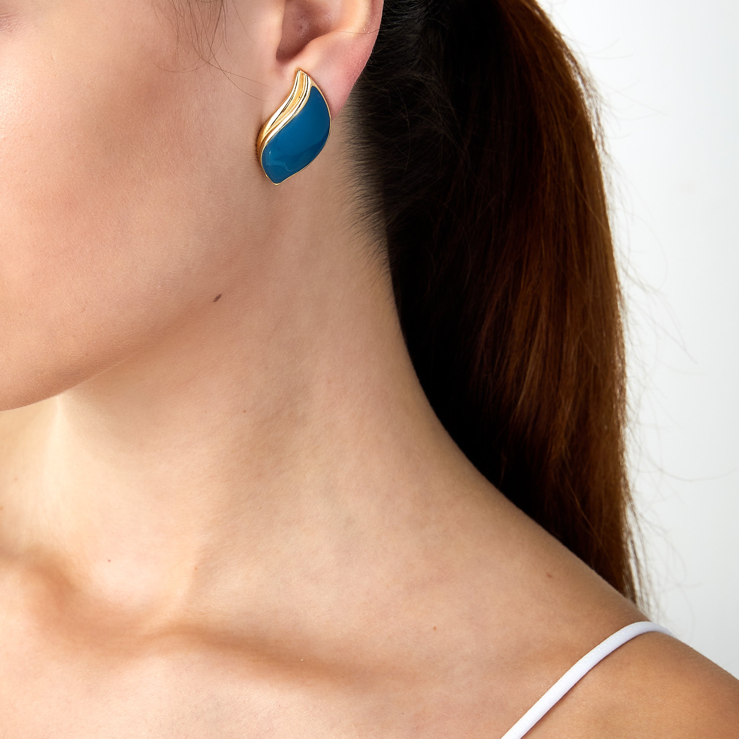 Vintage leaf clip earrings in teal enamel worn on woman’s ear