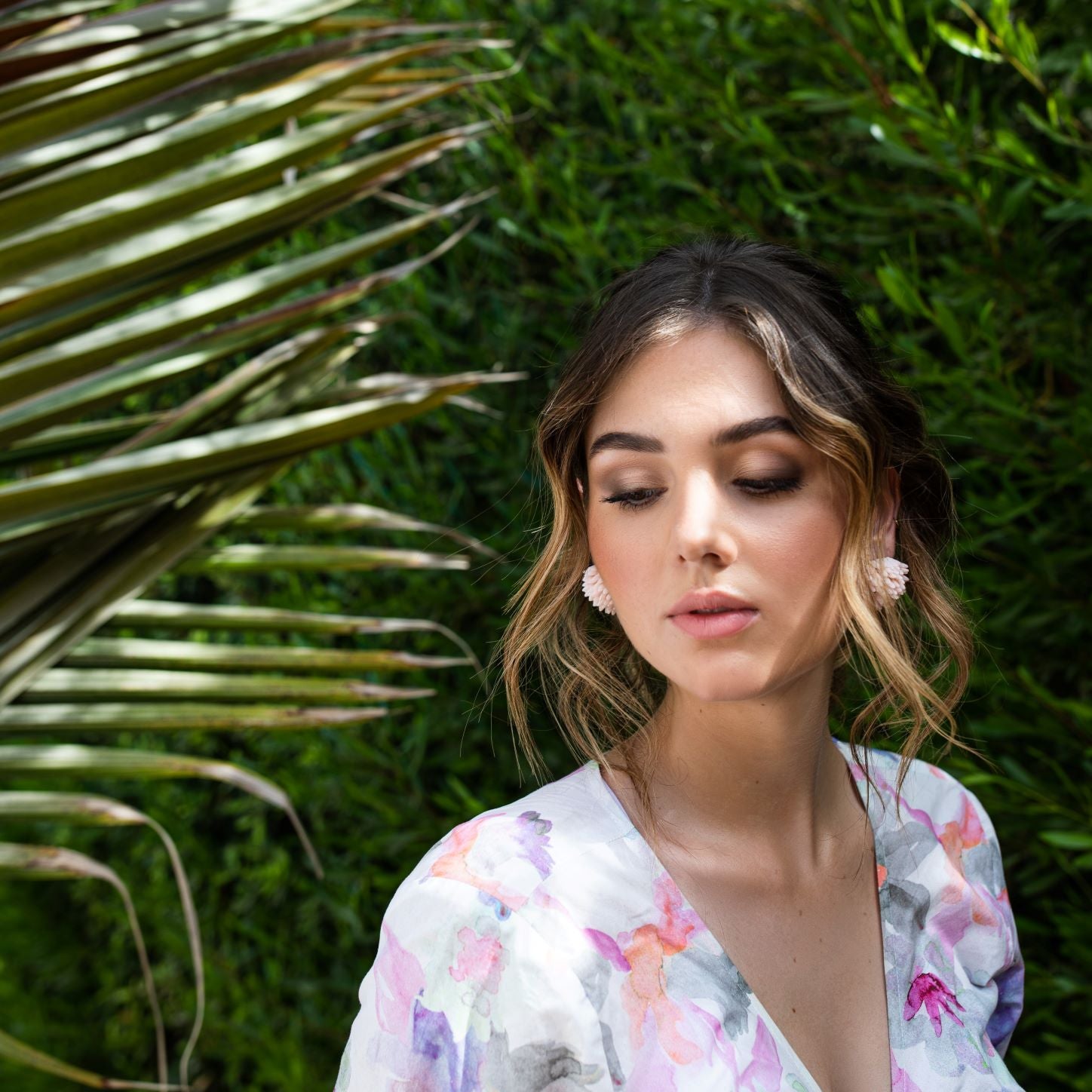 Woman under a palm tree wearing vintage Sandor clip earrings