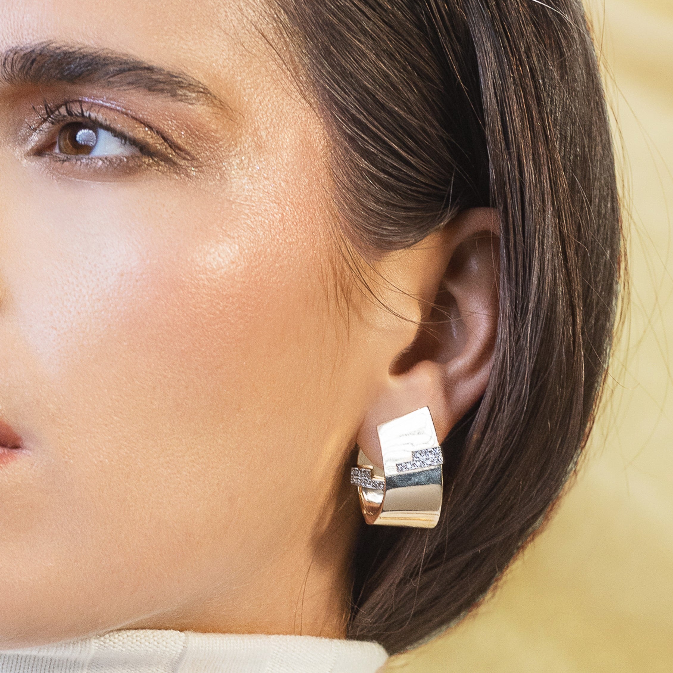 Italian retro earrings in 14ct gold and diamonds worn on a woman’s ear.